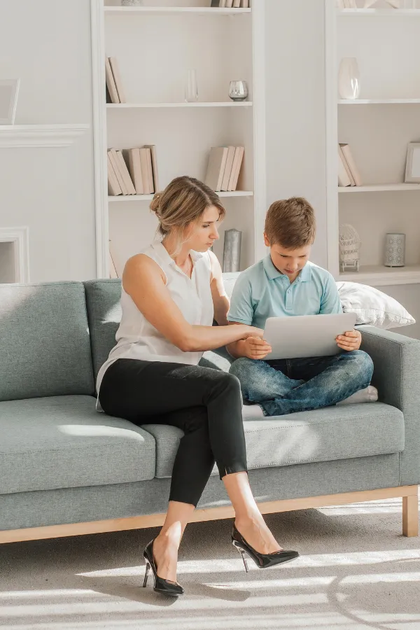 Leena sitting on the couch with her son, using a tablet together, reflecting her passion for learning and sharing knowledge.